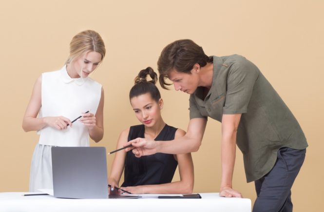 Three people gathered around a laptop.