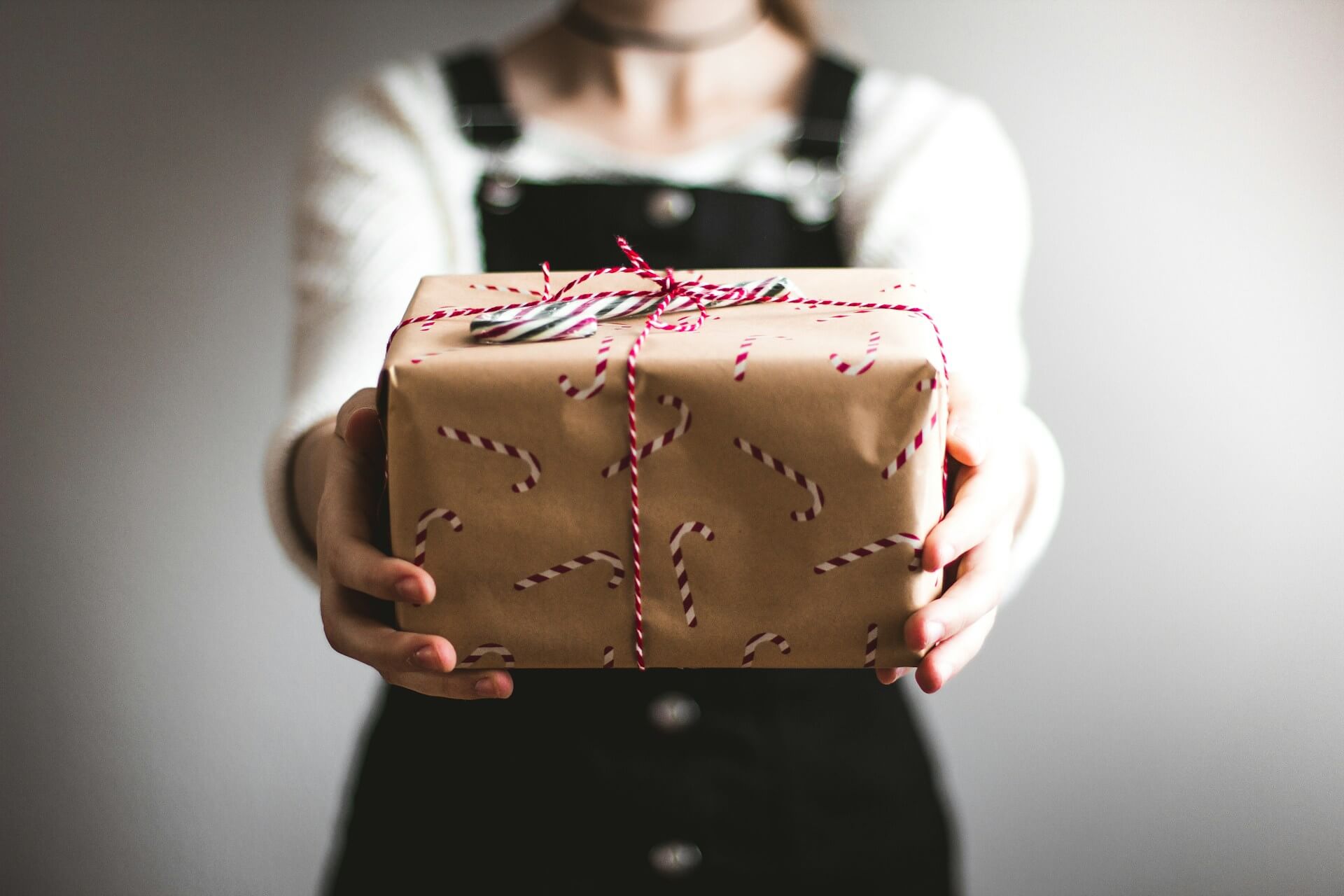 A person holding a present with candy can wrapping paper