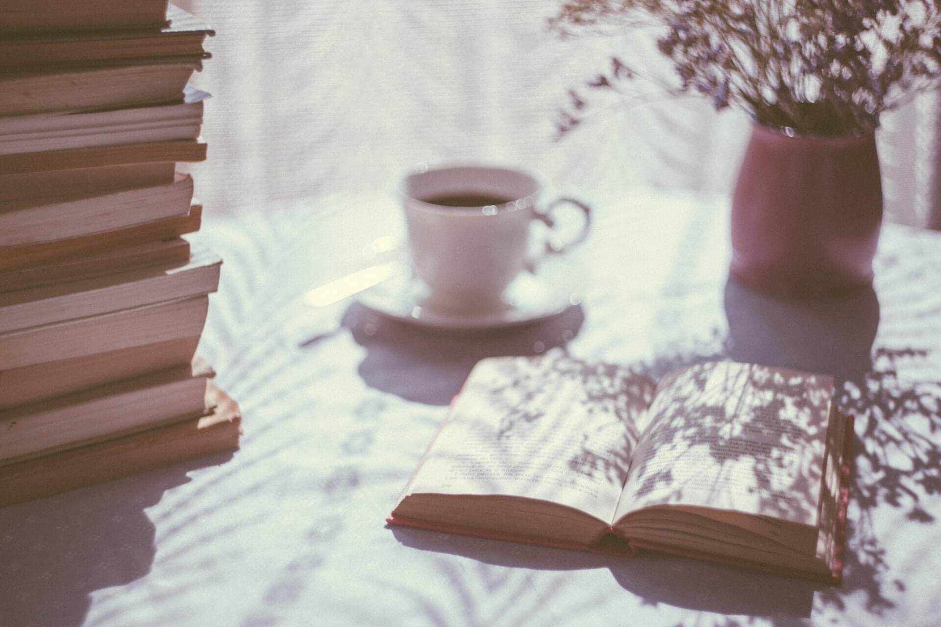 A coffee cup and a stack of books sitting on a table.