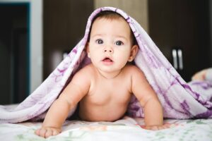 Writing after having a baby — a baby laying on her belly with a purple blanket over her head
