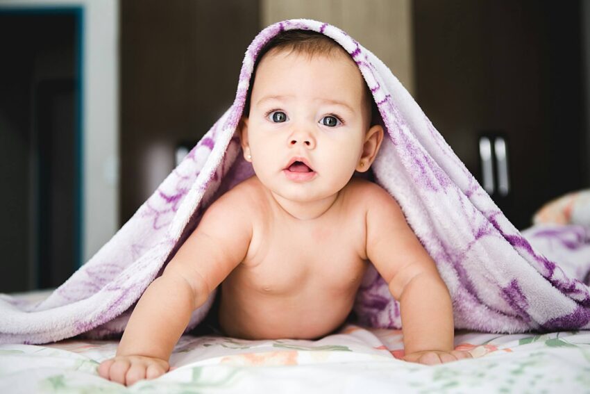 Writing after having a baby — a baby laying on her belly with a purple blanket over her head